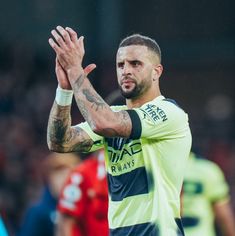 a soccer player is applauding with his hands in the air as he looks on