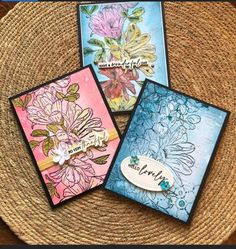 three cards with flowers on them sitting on top of a woven place mat next to a wicker basket