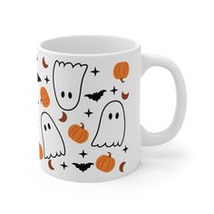 a white coffee mug with halloween ghost and pumpkins on the inside, all over it