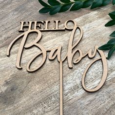 a wooden cake topper with the word hello baby on it