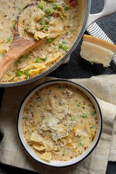 two bowls filled with pasta and peas on top of a cloth next to a wooden spoon