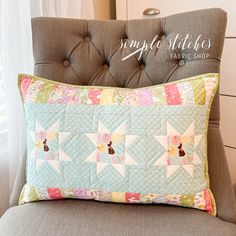 a pillow sitting on top of a chair in front of a window with the words simply stitches fabric shop