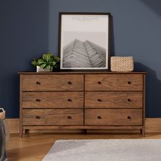 a wooden dresser sitting on top of a hard wood floor next to a blue wall