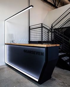 a black and white reception desk in an office with staircases to the second floor