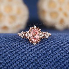 a pink diamond ring sitting on top of a blue cloth