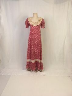 "vintage 1970s full length dress empire waist red/white floral print lace trim puff short sleeve w/elastic ruffled cuff scoop neck empire waist ruffle skirt hem lace around neck looks older, like antique lace perhaps tie back zipper up back 50/50 cotton/polyester good vintage condition, light wear label size 11/12-n/a-see below measures, lying flat, shoulder-14 1/2\" sleeve-10\" chest-17\" waist-15\" length-56 1/2\"" 70s Empire Waist Dress, Fitted Floor-length Vintage Dress For Spring, Fitted Vintage Floor-length Dress, Fitted Short Sleeve Maxi Dress With Lace Trim, Fitted Maxi Dress With Lace Trim And Short Sleeves, Fitted Floor-length Vintage Dress, Fitted Victorian Cotton Prairie Dress, Vintage Prairie Dress Maxi Length, Victorian Cotton Prairie Dress