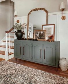 a large mirror sitting on top of a dresser next to a stair case in a living room