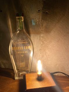 an empty bottle sitting on top of a wooden table next to a small light bulb