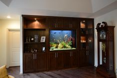 a living room with a fish tank in the center and wooden cabinets on both sides