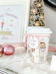 a coffee cup sitting on top of a white fur covered floor next to a christmas tree