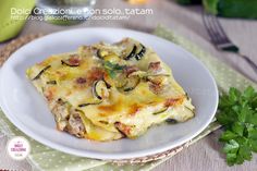 a white plate topped with lasagna covered in cheese and toppings next to parsley