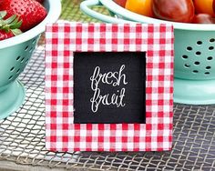 a red and white checkered table cloth with a black sign that says fresh fruit