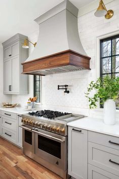 a stove top oven sitting inside of a kitchen next to white cabinets and wooden floors