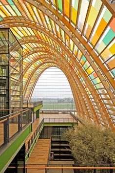 the inside of a building with colorful glass and wood beams on it's ceiling