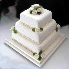 a three tiered white wedding cake with flowers on top