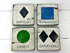 four square wooden signs with different colors on them, each depicting an arrow and the words difficult, intermediaate, expert only