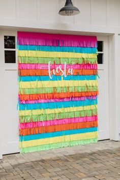 a multicolored wall hanging on the side of a garage door that says fiesta