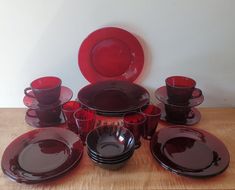 a table topped with lots of red dishes and cups on top of a wooden table