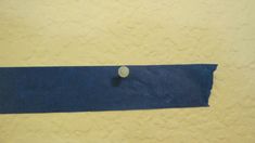 a blue piece of cloth with a button on it sitting next to a white wall