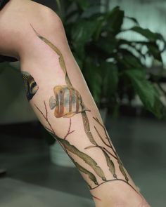 a person with a tattoo on their leg that has fish and seaweed in it