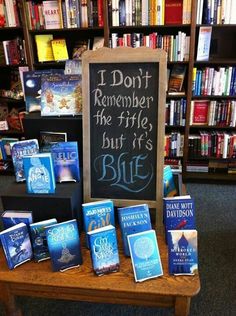 a table with books on it and a sign that says i don't remember the title but it's blue