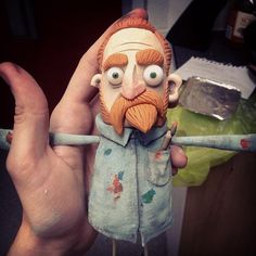 a close up of a person holding a doll with an orange beard and mustache on it's head