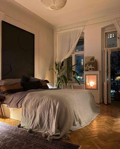 a bedroom with a bed, desk and window in the background at night time is lit by candles