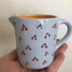 a hand holding a cup with cherries on it