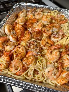 a pan filled with shrimp and pasta on top of a stove