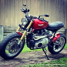 a red and black motorcycle parked in front of a wooden building