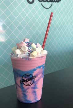 a pink and blue drink with marshmallows in it sitting on a table