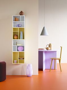 an orange floor in front of a white wall with shelves on it and a chair next to the table