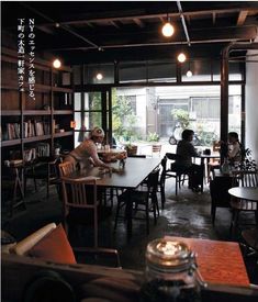 people are sitting at tables in the middle of a room with lots of bookshelves