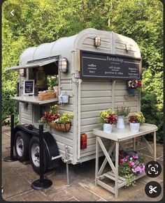 an old trailer converted into a coffee shop with potted plants and flowers on the side