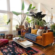 a living room filled with lots of furniture and plants on top of wooden flooring