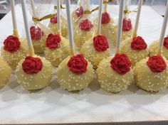 some cake pops with red roses on them and white sticks in the middle are lined up next to each other