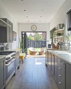 a kitchen with gray cabinets and white walls, along with a clock on the wall