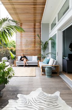 a woman sitting on top of a couch in a living room next to a plant