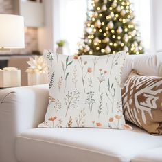 a living room with a christmas tree in the background and pillows on the couches