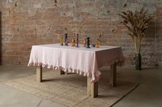 a table with a cloth on it and chess pieces sitting on top of it, in front of a brick wall