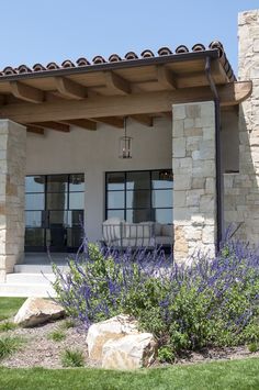 an outdoor living area with stone walls and purple flowers