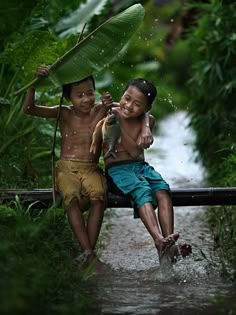 two young boys sitting on a bench in the rain