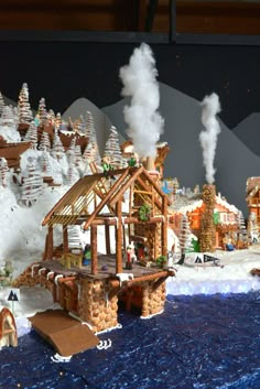 an elaborate gingerbread house on display in front of snow - covered mountains and trees