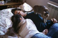 a woman laying in bed next to a cat