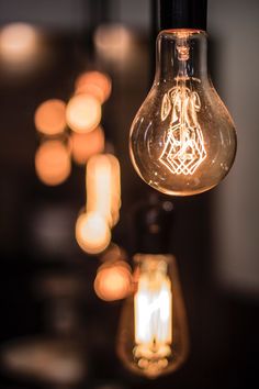 a light bulb hanging from a ceiling with candles in the background