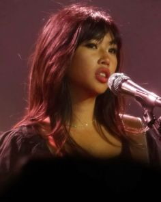 a woman with red hair singing into a microphone