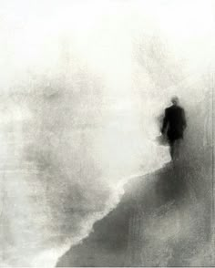 a black and white photo of a person walking on the beach in the foggy water