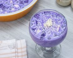 a purple dessert in a glass on top of a table next to other food items