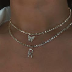 a close up view of a woman's neck with a butterfly pendant on it