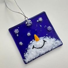 a glass ornament with a snowman on it's face in the snow